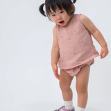 Bebê vestindo Regata Duda em linho rosa antigo bordada com abelhas e tapa-fralda no mesmo tecido.
