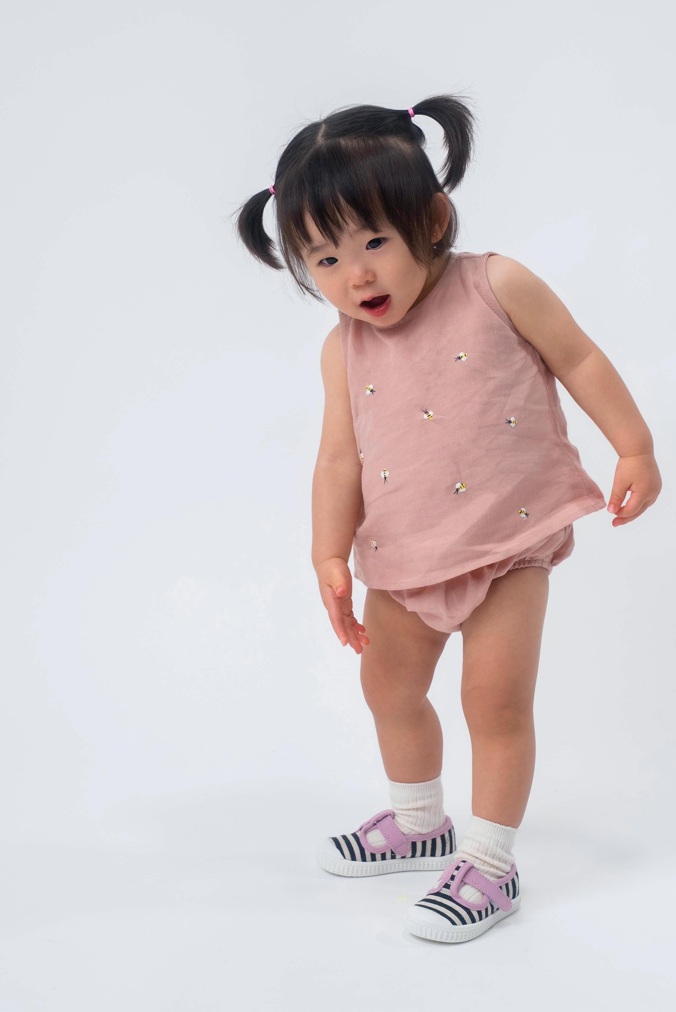 Bebê vestindo Regata Duda em linho rosa antigo bordada com abelhas e tapa-fralda no mesmo tecido.