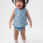 Bebê vestindo Conjunto Duda em linho azul celeste, com regata bordada à mão e tapa-fralda.