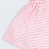 Detalhe da saia infantil em linho listrado rosa e branco, mostrando tecido leve com listras finas e cintura elástica.