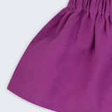 Close de saia infantil em linho roxo com cós elástico e caimento leve.