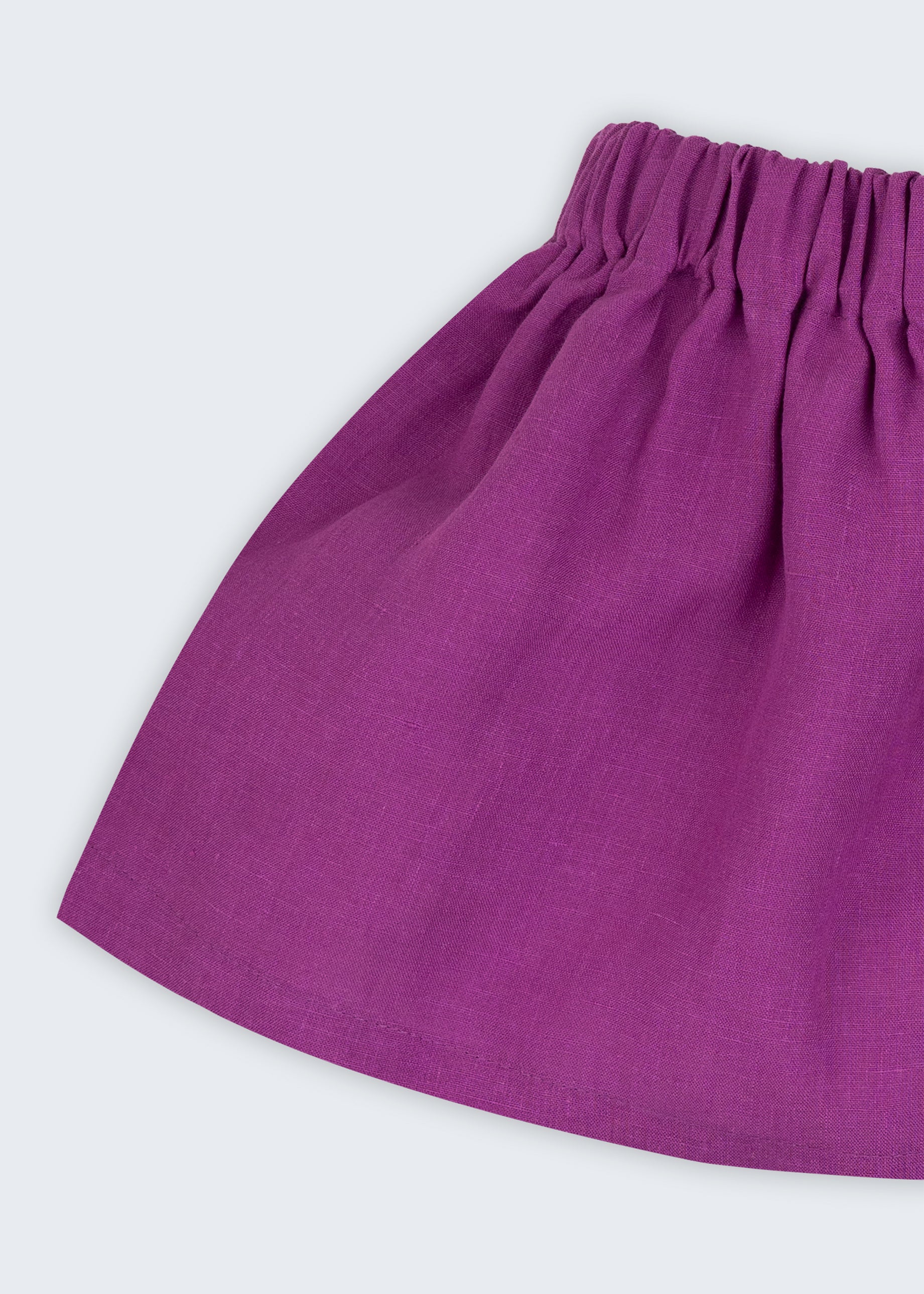 Close de saia infantil em linho roxo com cós elástico e caimento leve.