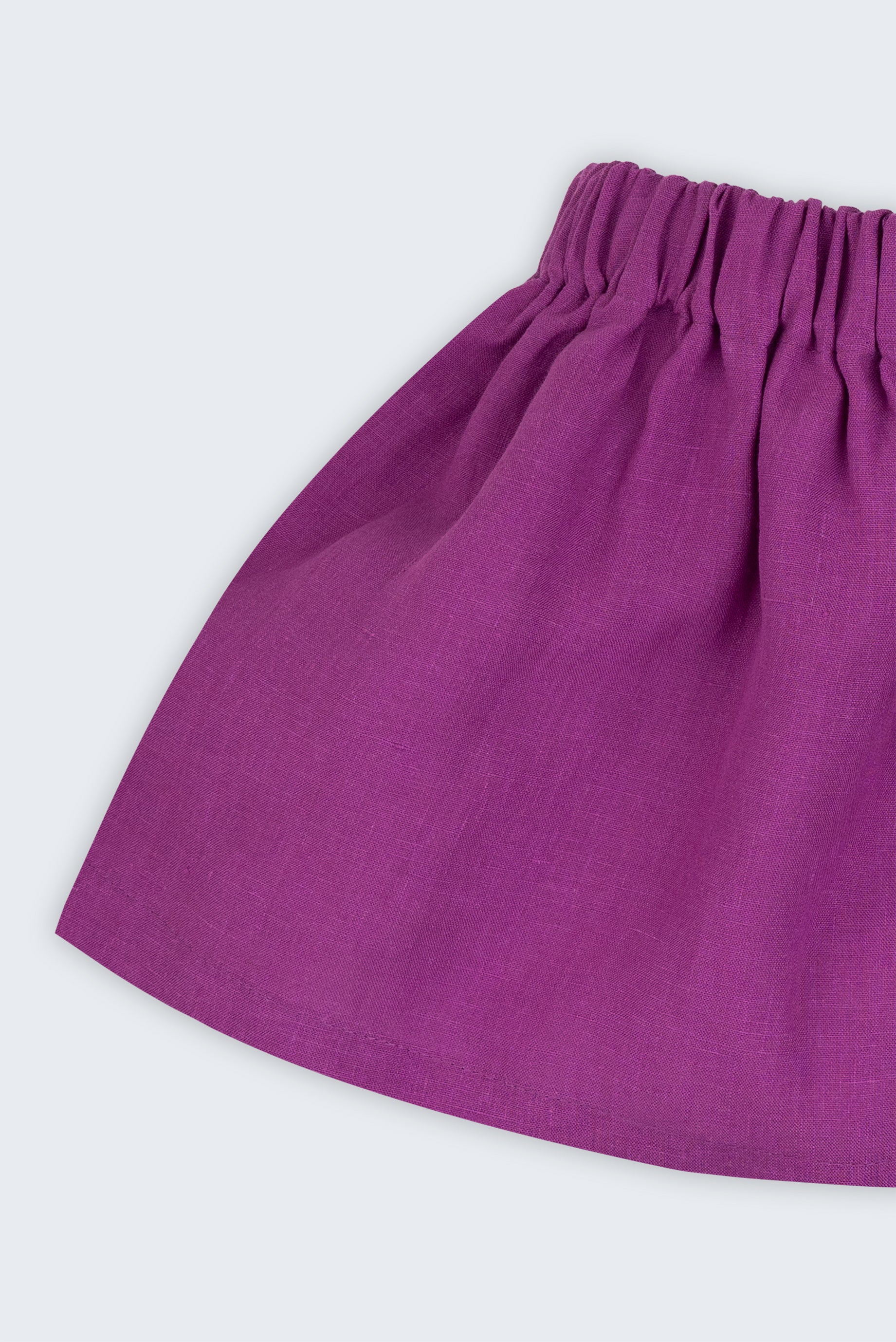 Close de saia infantil em linho roxo com cós elástico e caimento leve.