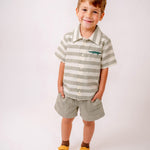 Menino vestindo shorts infantil verde oliva com camisa listrada em mesmo tom com bordado de jacaré