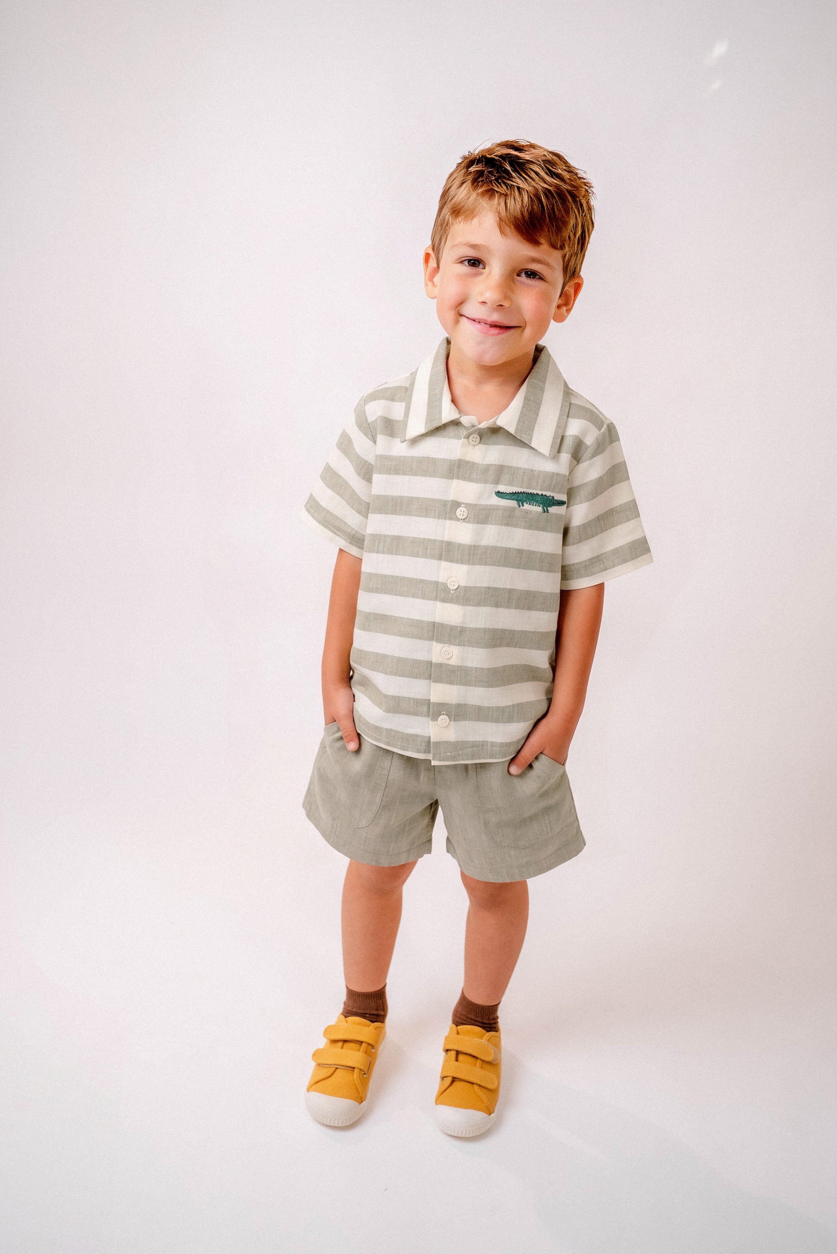 Menino vestindo shorts infantil verde oliva com camisa listrada em mesmo tom com bordado de jacaré