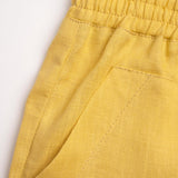 Detalhe do shorts infantil em linho amarelo com bolso frontal e cintura de elástico
