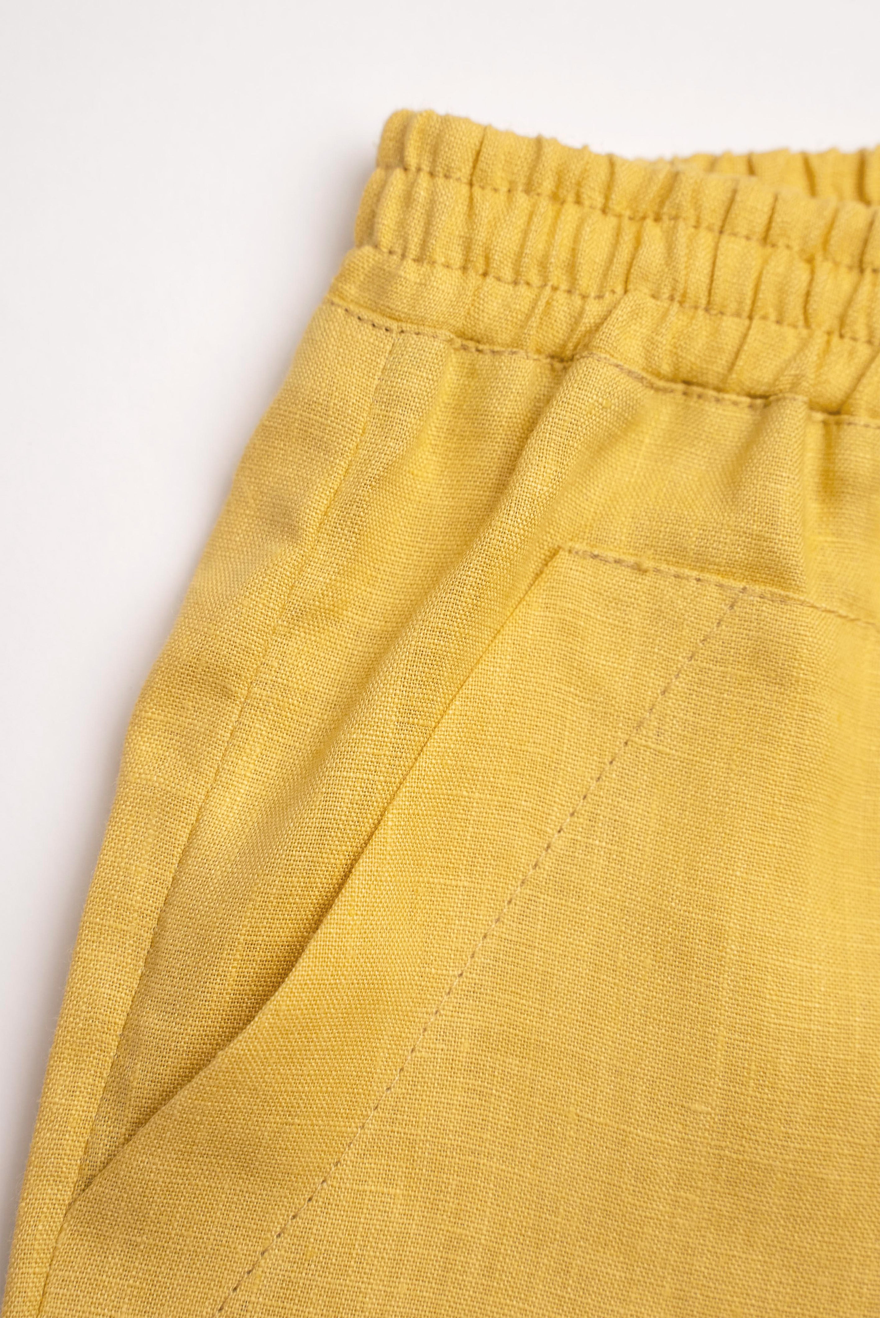Detalhe do shorts infantil em linho amarelo com bolso frontal e cintura de elástico