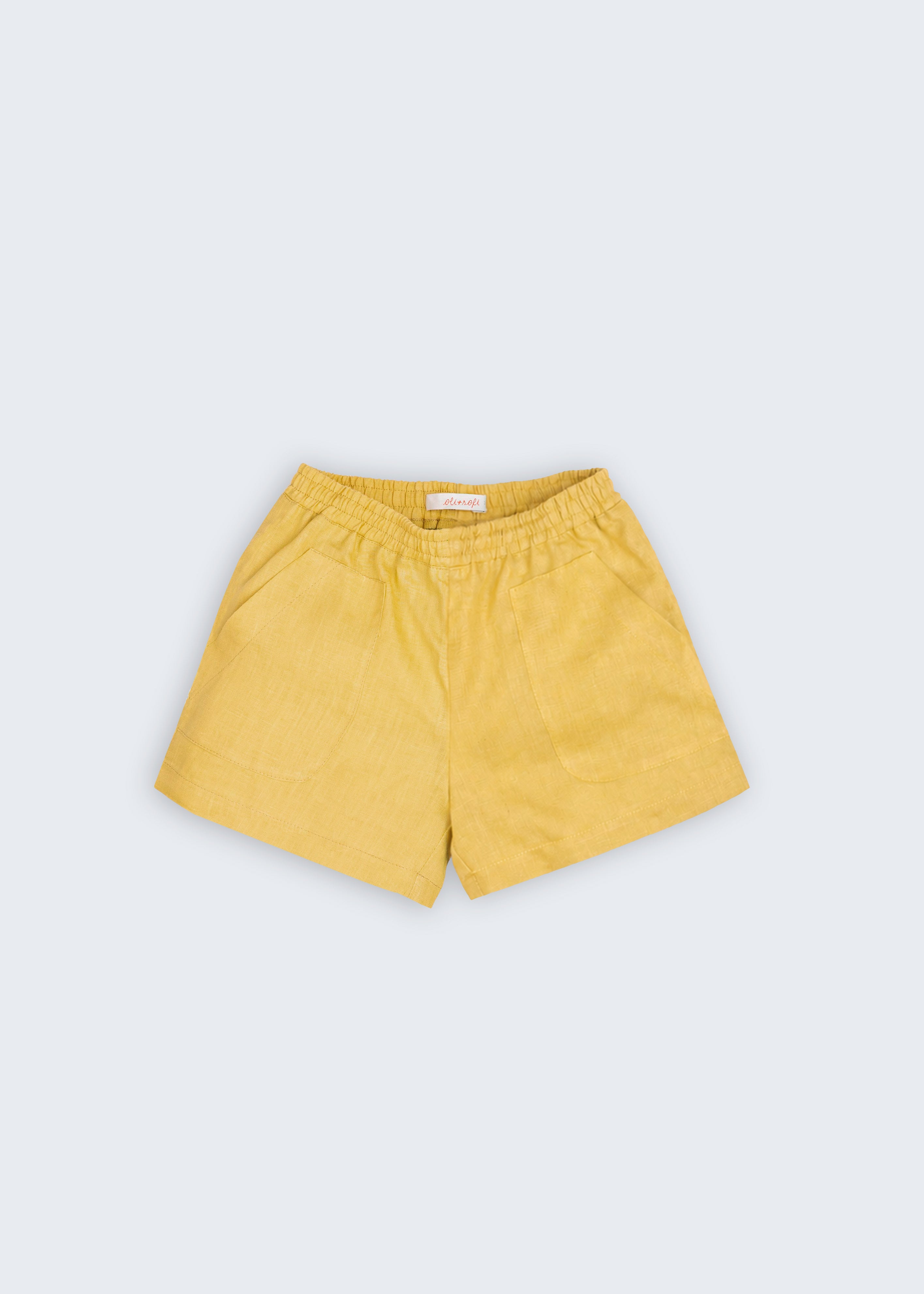 Shorts infantil em linho puro amarelo com cintura de elástico e bolsos frontais, visto de frente