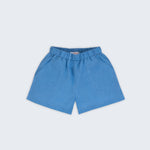 Shorts infantil em linho puro azul capri com bolsos frontais e cintura elástica para meninos e meninas, visto de frente.