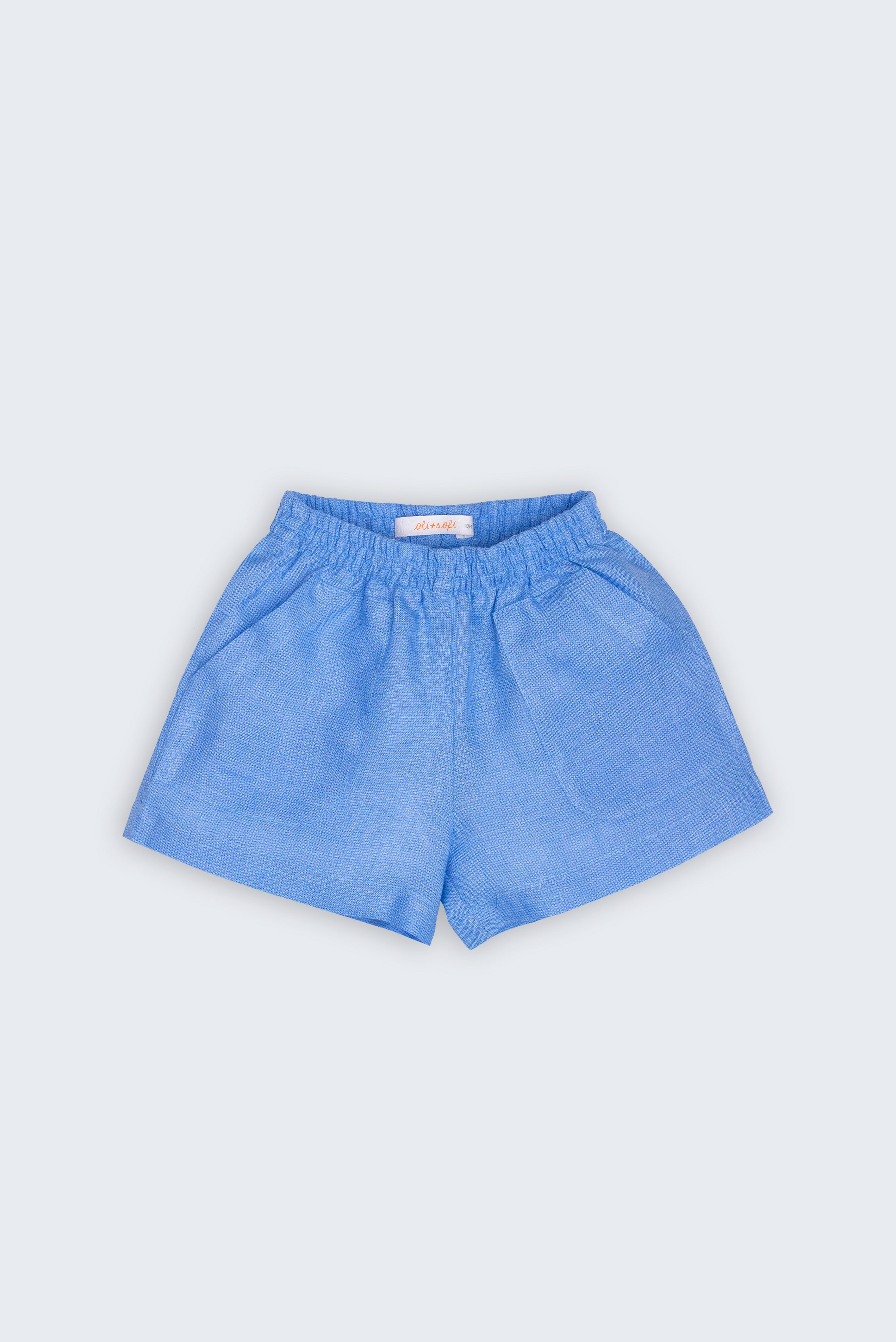 Shorts Chico infantil em 100% linho azul índigo claro, fotografado de frente, com cintura de elástico e bolsos frontais.