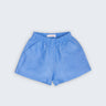 Shorts Chico infantil em 100% linho azul índigo claro, fotografado de frente, com cintura de elástico e bolsos frontais.