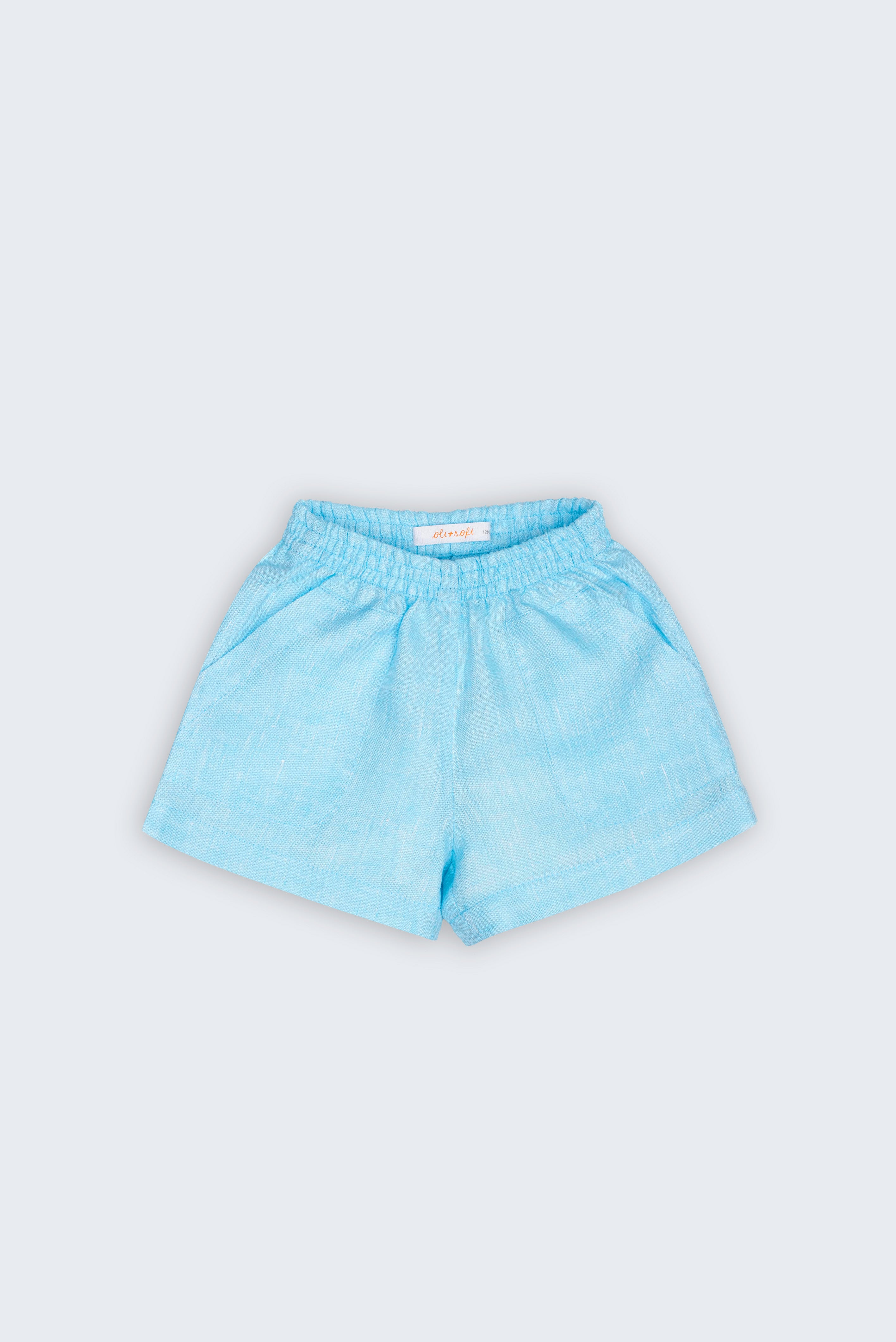 Shorts Chico infantil em 100% linho azul turquesa fotografado de frente, com cintura de elástico e bolsos frontais.