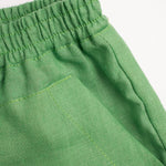 Detalhe do shorts infantil verde em linho puro com bolso frontal.