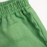 Detalhe do shorts infantil verde em linho puro com bolso frontal.