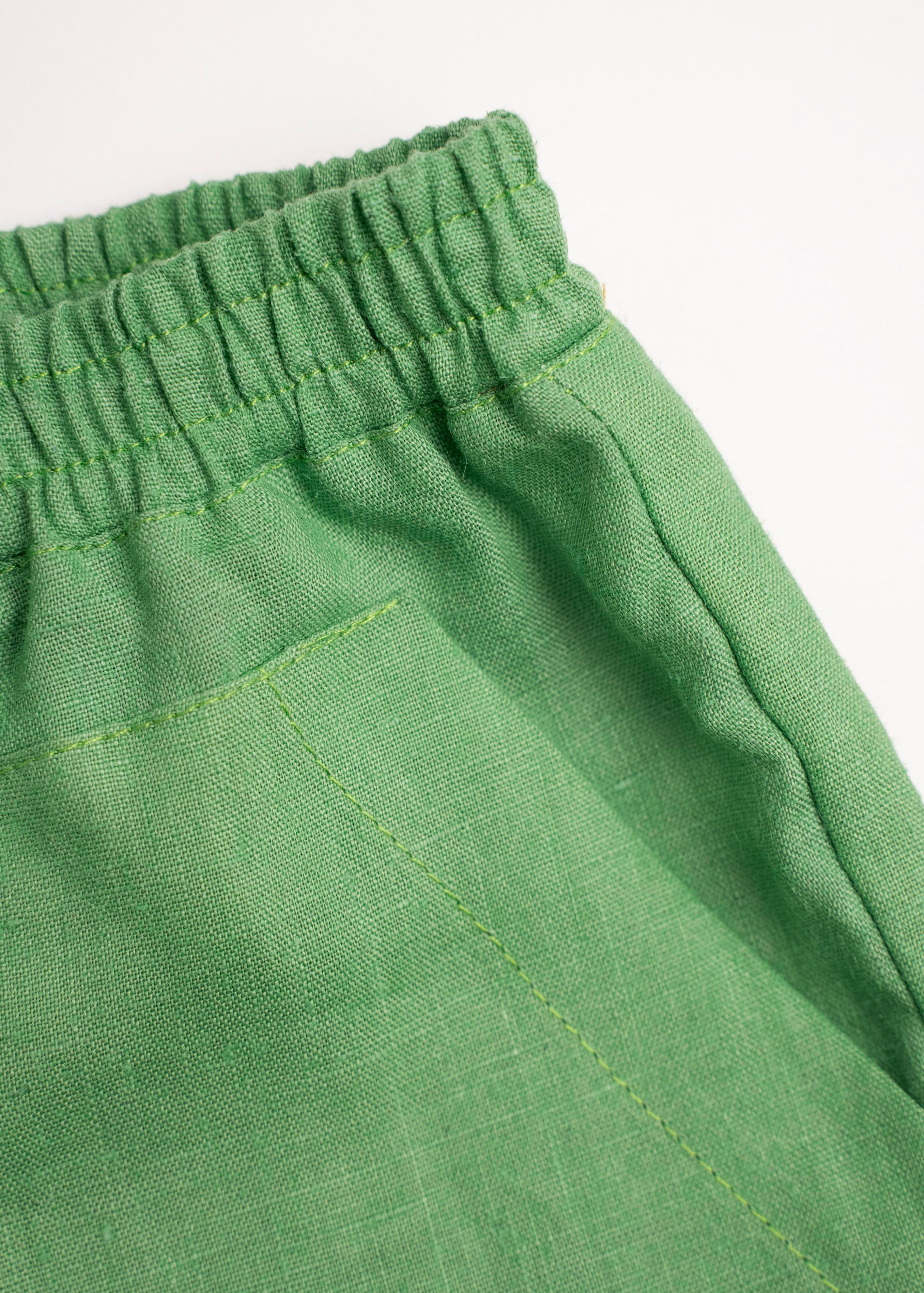 Detalhe do shorts infantil verde em linho puro com bolso frontal.
