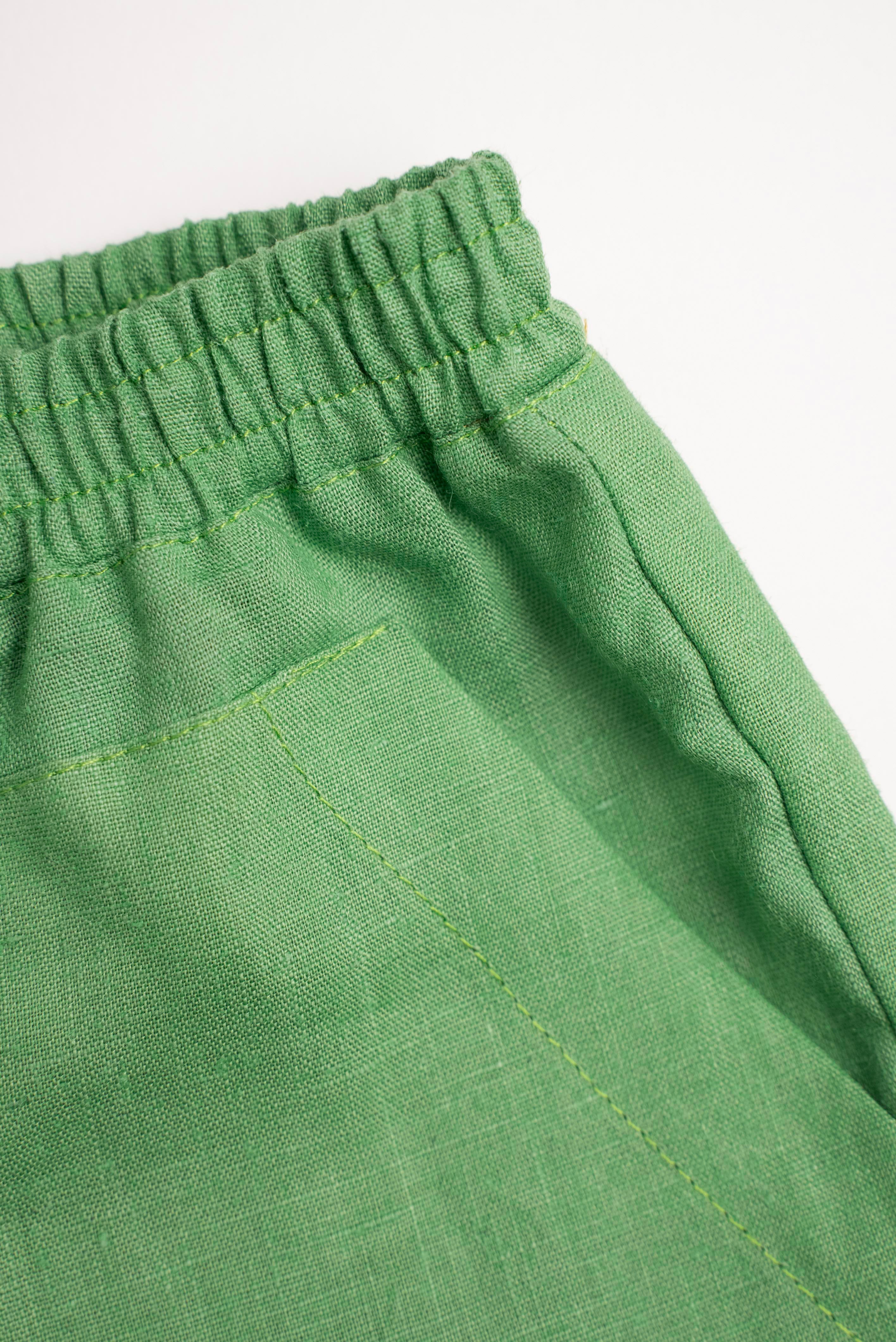 Detalhe do shorts infantil verde em linho puro com bolso frontal.