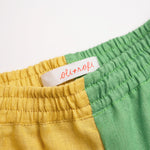 Detalhe da cintura de elástico do shorts infantil em linho bicolor verde e amarelo