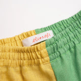 Detalhe da cintura de elástico do shorts infantil em linho bicolor verde e amarelo