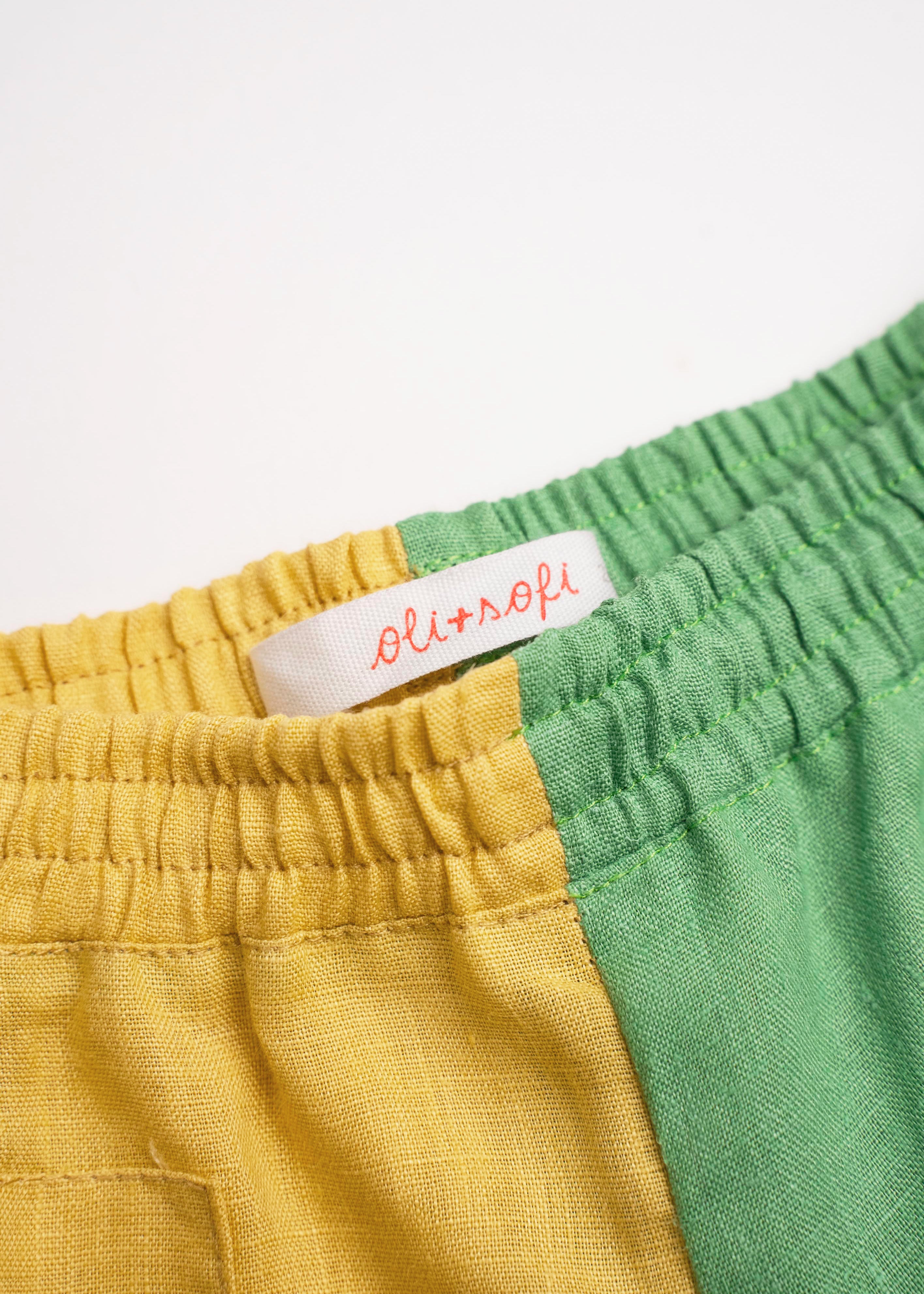 Detalhe da cintura de elástico do shorts infantil em linho bicolor verde e amarelo