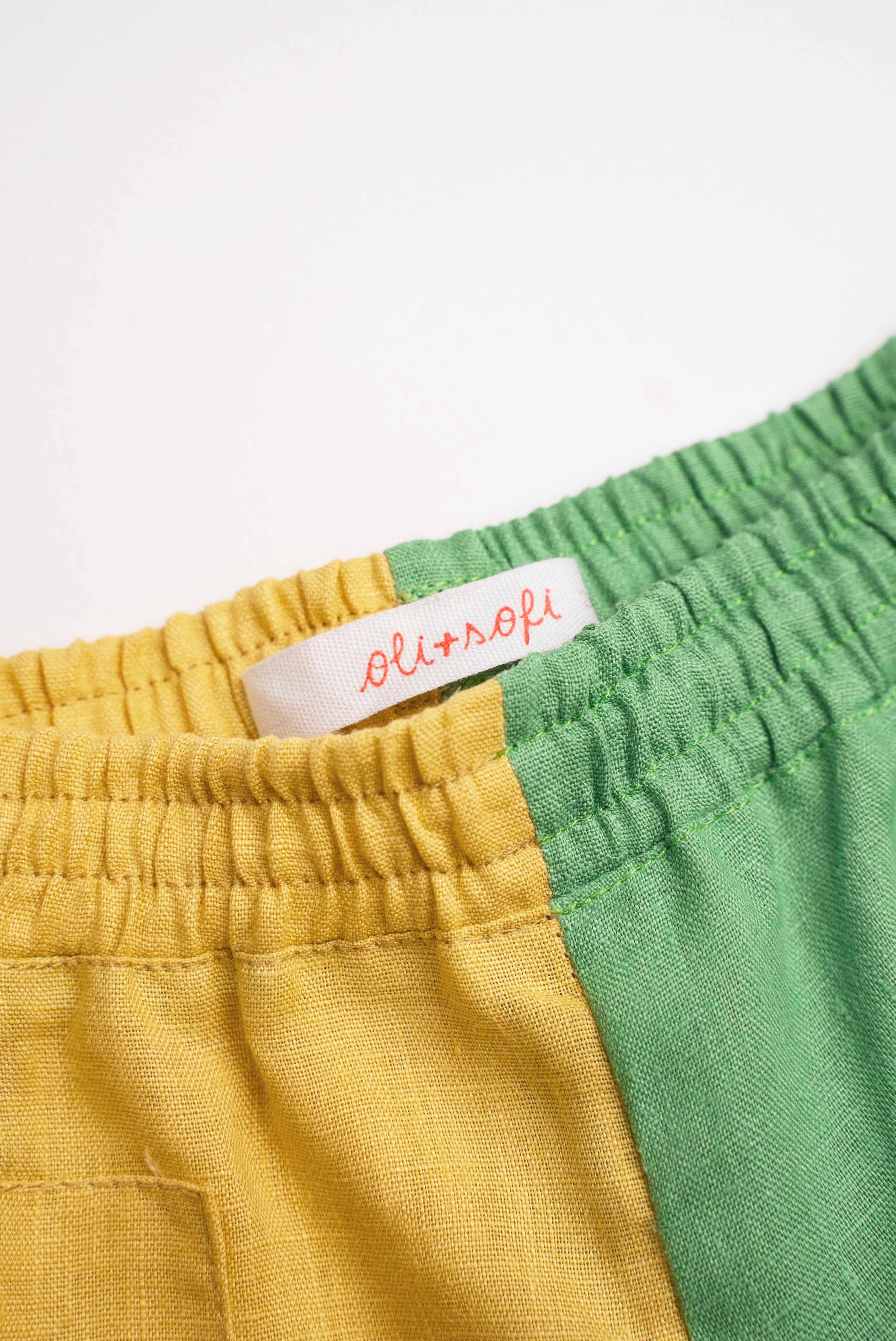 Detalhe da cintura de elástico do shorts infantil em linho bicolor verde e amarelo