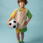 Menino usando shorts infantil bicolor verde e amarelo em linho puro, combinado com camisa bordada de futebol