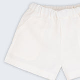 Shorts infantil em linho puro branco com bolsos frontais e cintura elástica para meninos e meninas, visto de frente em detalhe.