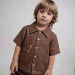 Menino vestindo shorts infantil em linho marrom em conjunto com camisa em mesmo tom da Oli e Sofi