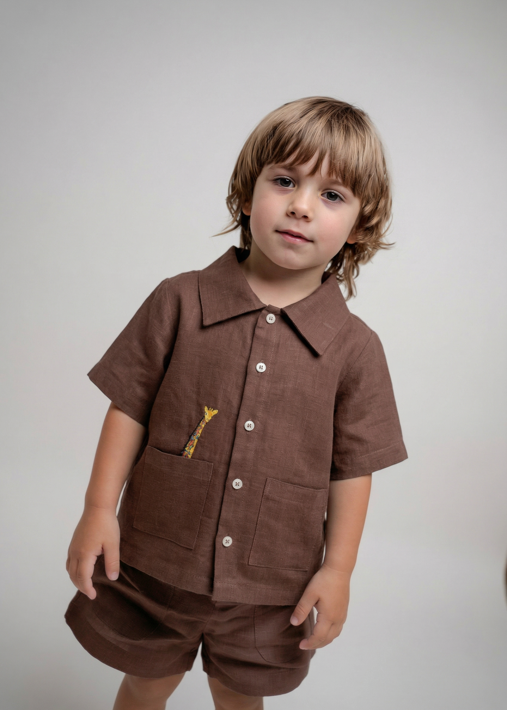 Menino vestindo shorts infantil em linho marrom em conjunto com camisa em mesmo tom da Oli e Sofi