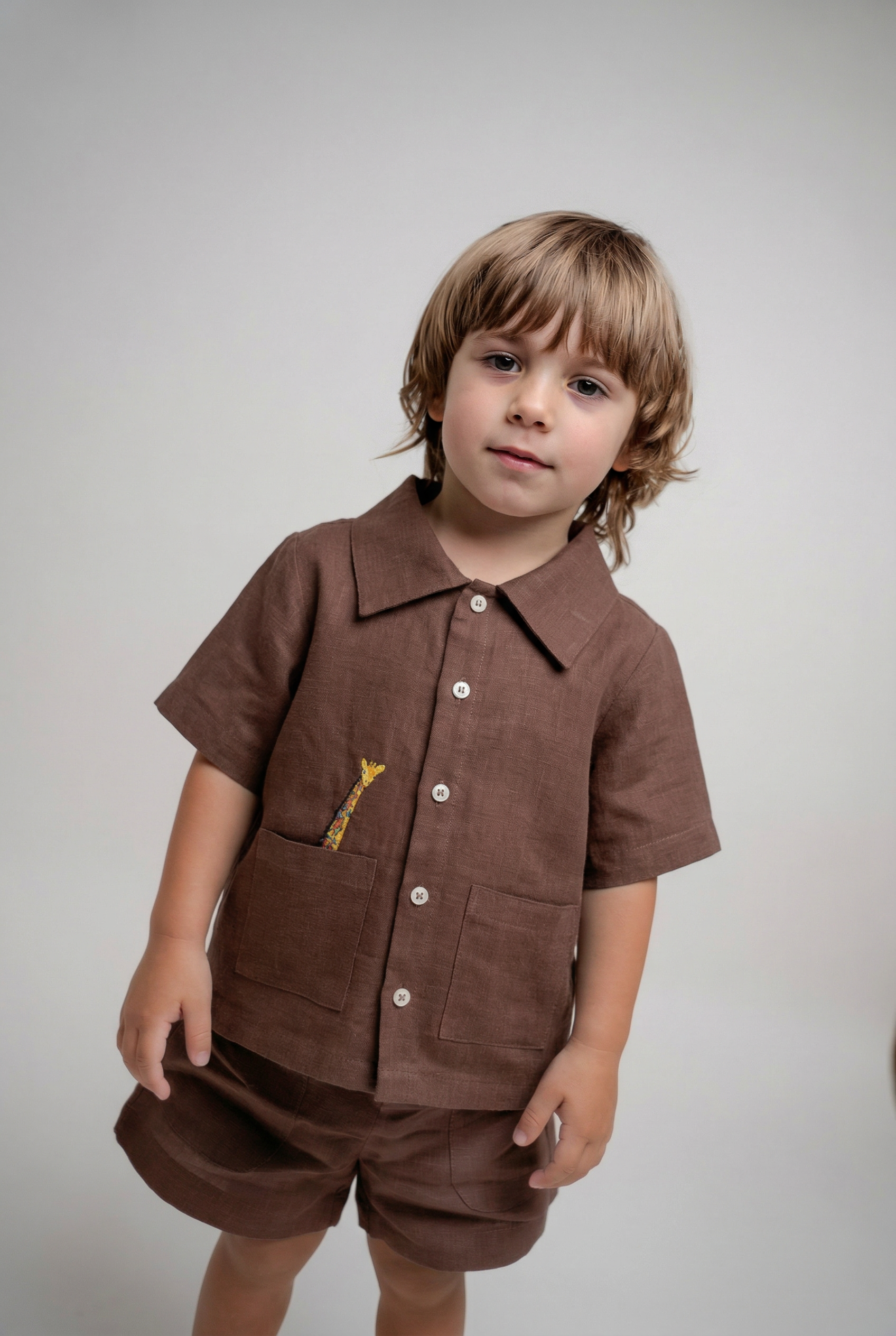 Menino vestindo shorts infantil em linho marrom em conjunto com camisa em mesmo tom da Oli e Sofi