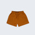 Shorts infantil em linho puro marrom terracota com bolsos frontais e cintura elástica para meninos e meninas, visto de frente.