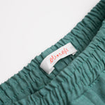 Detalhe da cintura de elástico do shorts infantil em linho verde