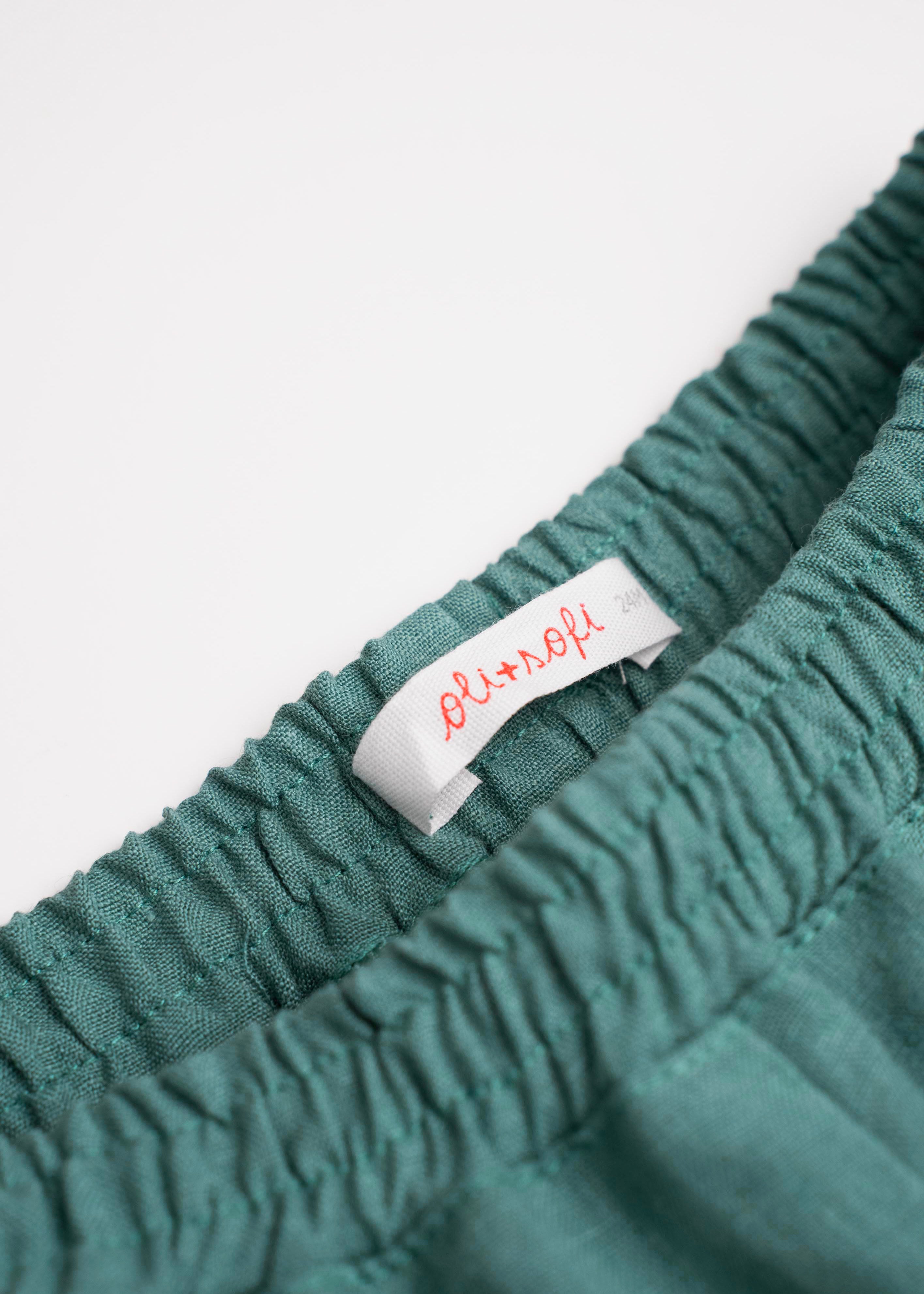 Detalhe da cintura de elástico do shorts infantil em linho verde