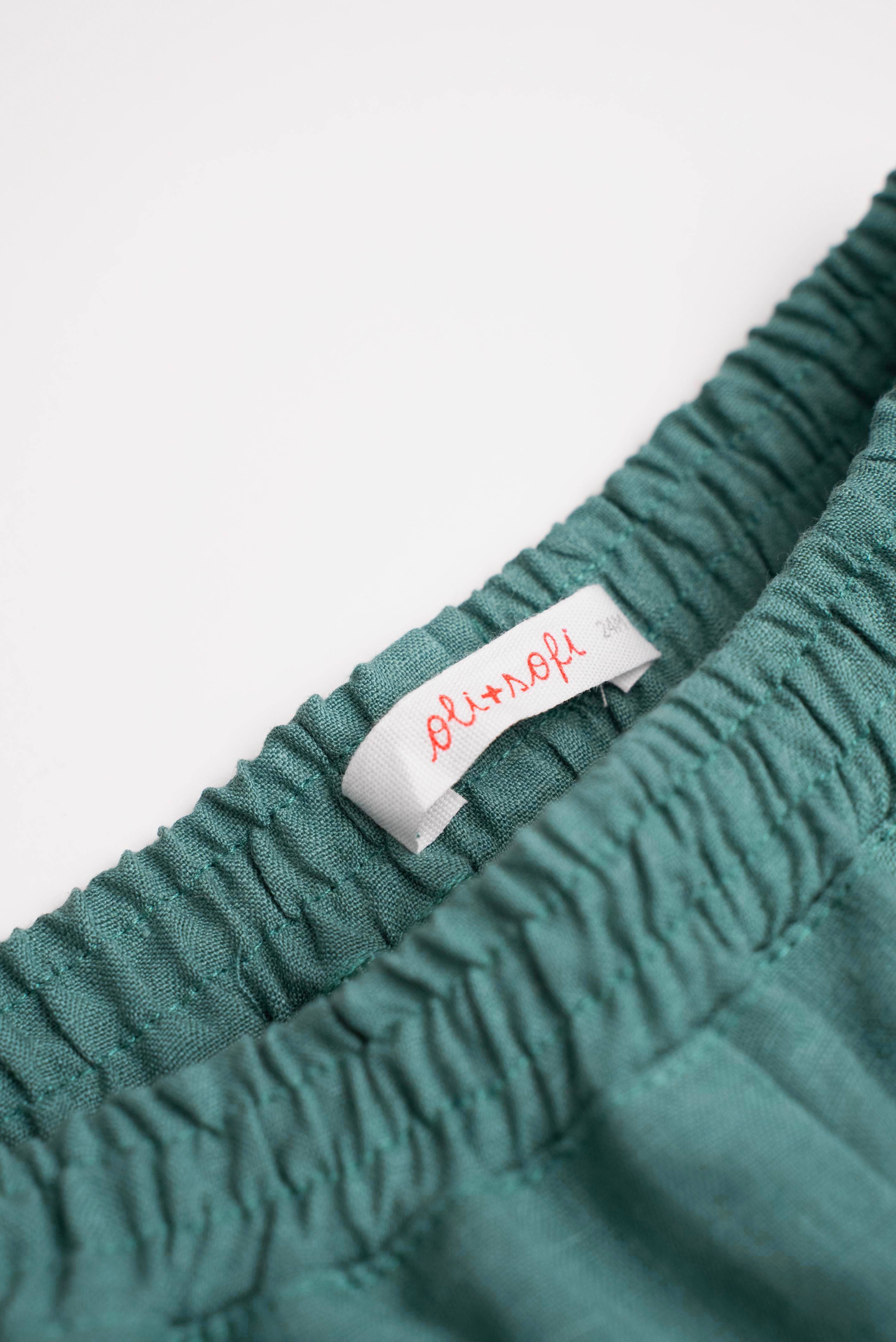 Detalhe da cintura de elástico do shorts infantil em linho verde