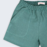 Detalhe do shorts infantil em linho verde com bolso frontal e textura natural do tecido