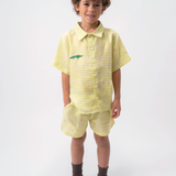 Menino vestindo Shorts Chico infantil em linho verde com listras brancas, combinado com camisa no mesmo tecido.