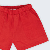 Close de shorts infantil em linho puro vermelho com bolsos frontais e cintura elástica.