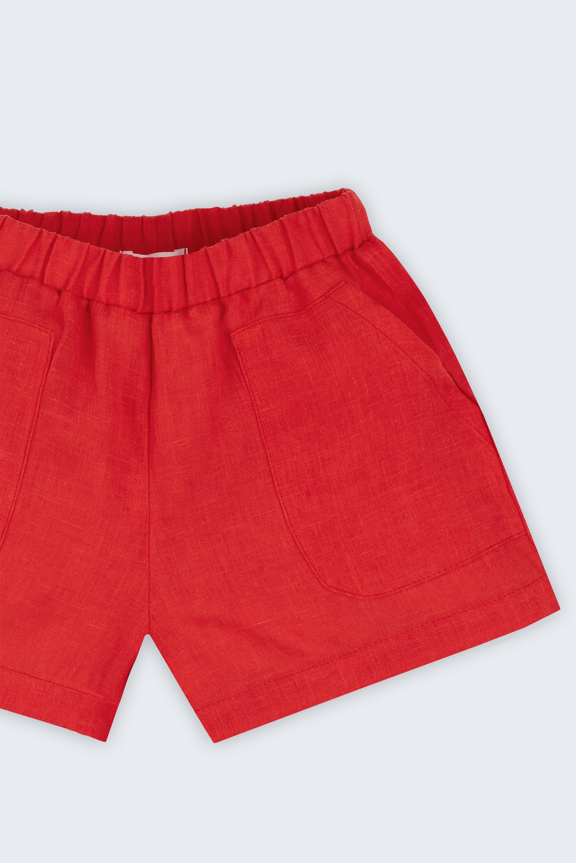 Close de shorts infantil em linho puro vermelho com bolsos frontais e cintura elástica.