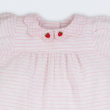 Close do vestido bebê em algodão listrado branco e rosa com gola xadrez bordada à mão com morangos.