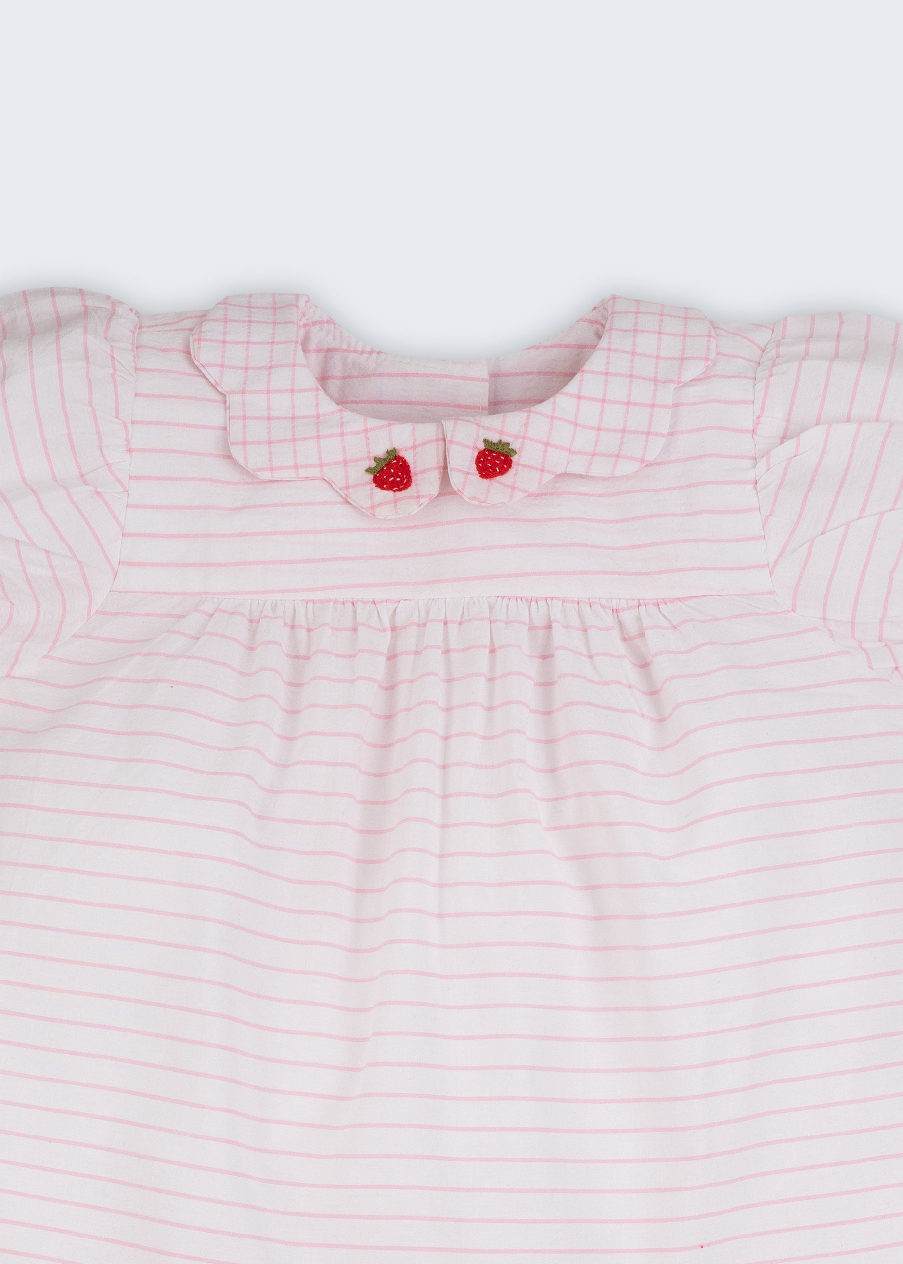 Close do vestido bebê em algodão listrado branco e rosa com gola xadrez bordada à mão com morangos.