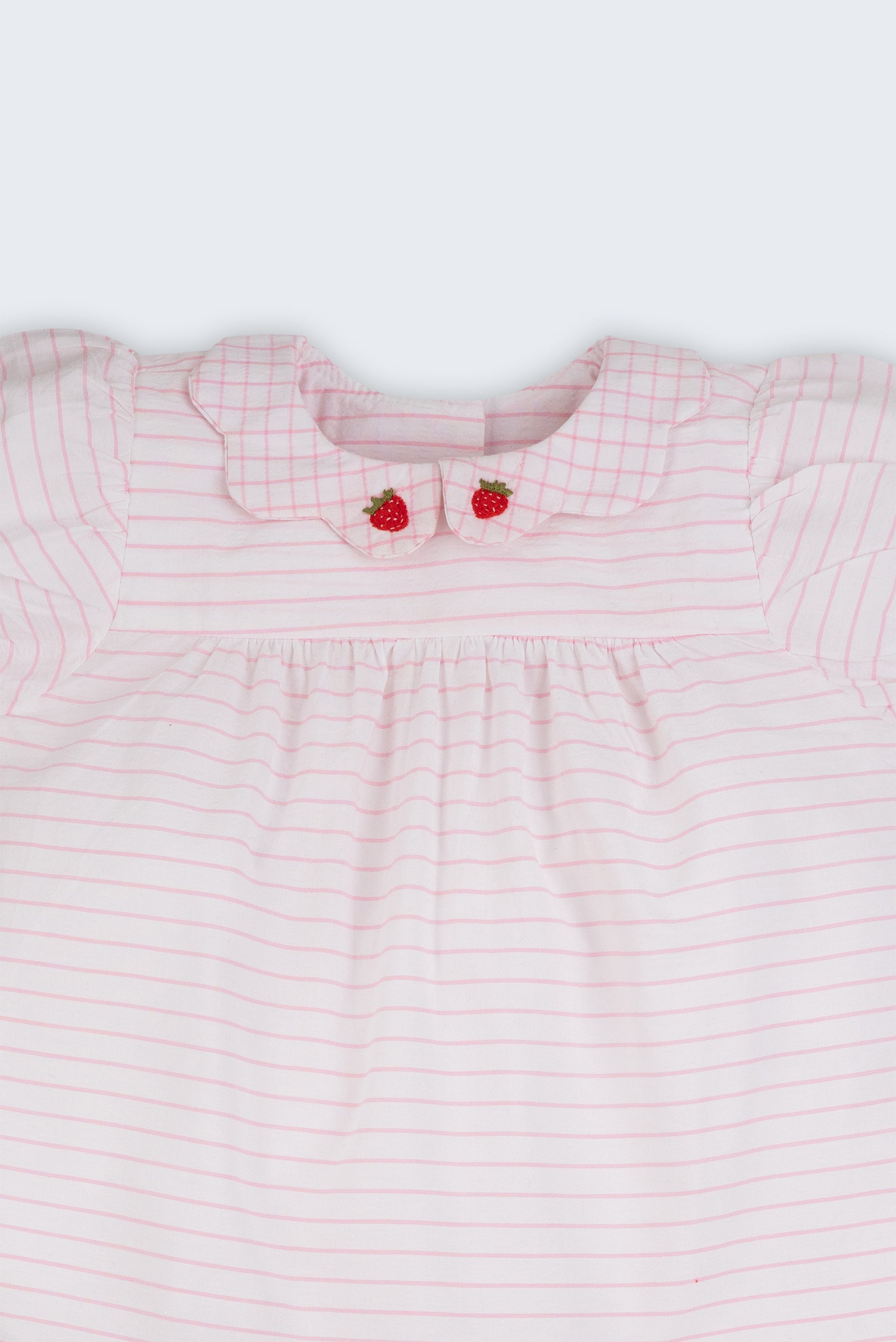 Close do vestido bebê em algodão listrado branco e rosa com gola xadrez bordada à mão com morangos.