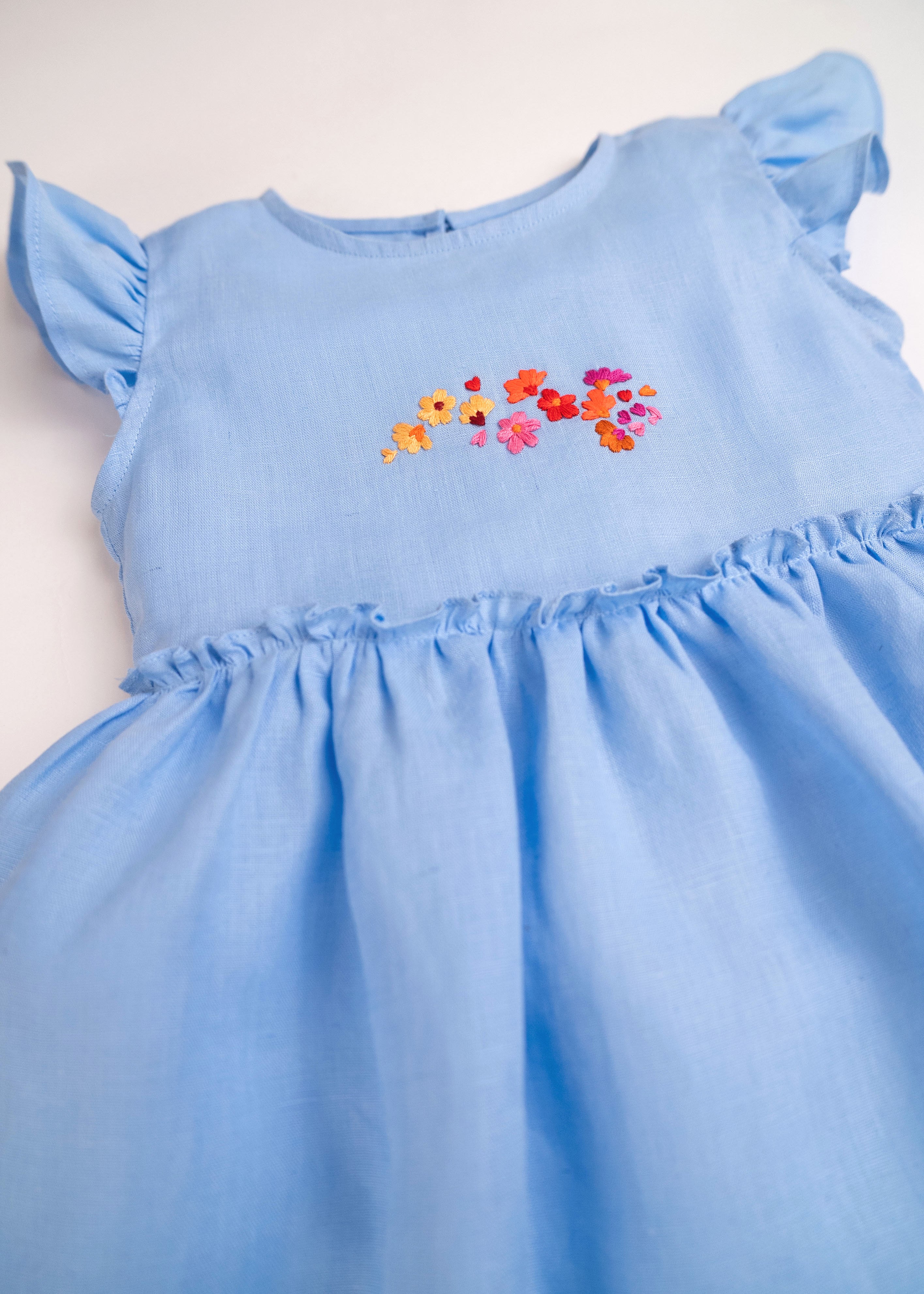 Detalhe do vestido infantil em linho azul-celeste com bordado de flores