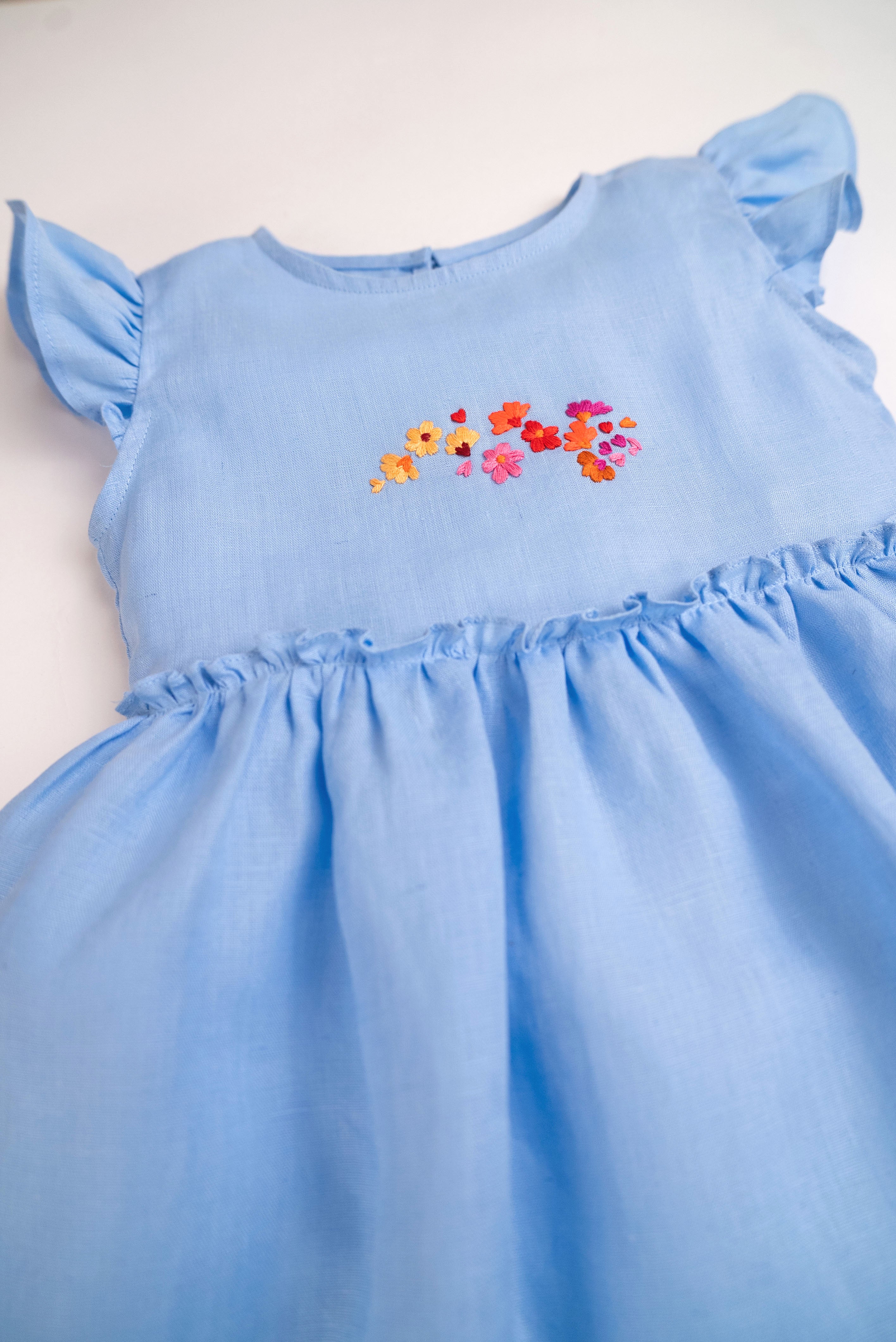 Detalhe do vestido infantil em linho azul-celeste com bordado de flores