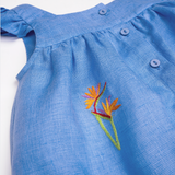 Detalhe do Vestido Clara em linho fio tinto azul índigo com helicônia bordada à mão, mangas em babado e botões frontais.