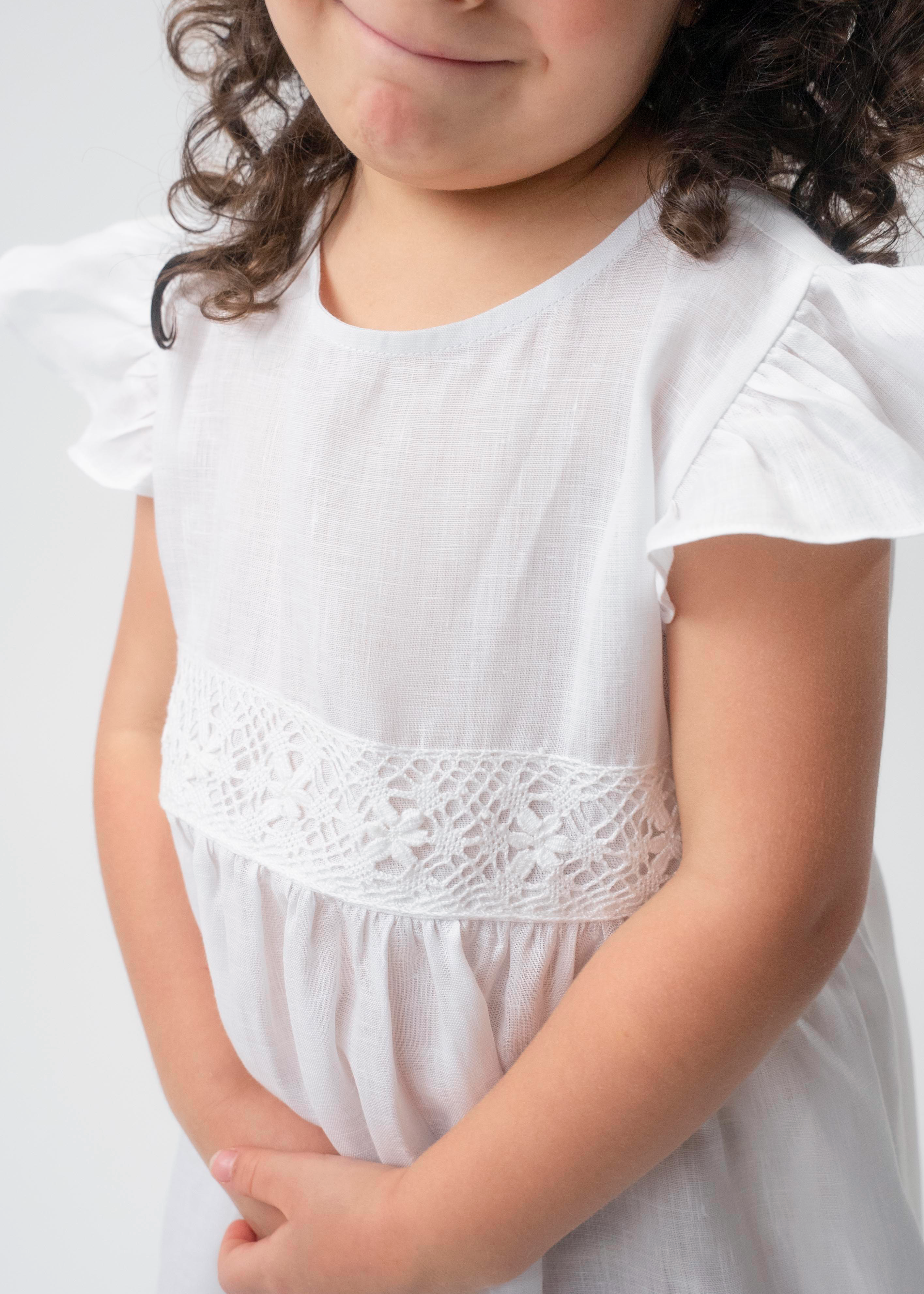 Detalhe da renda de bilro branca na cintura do Vestido Clara infantil em linho, com manga em babado.