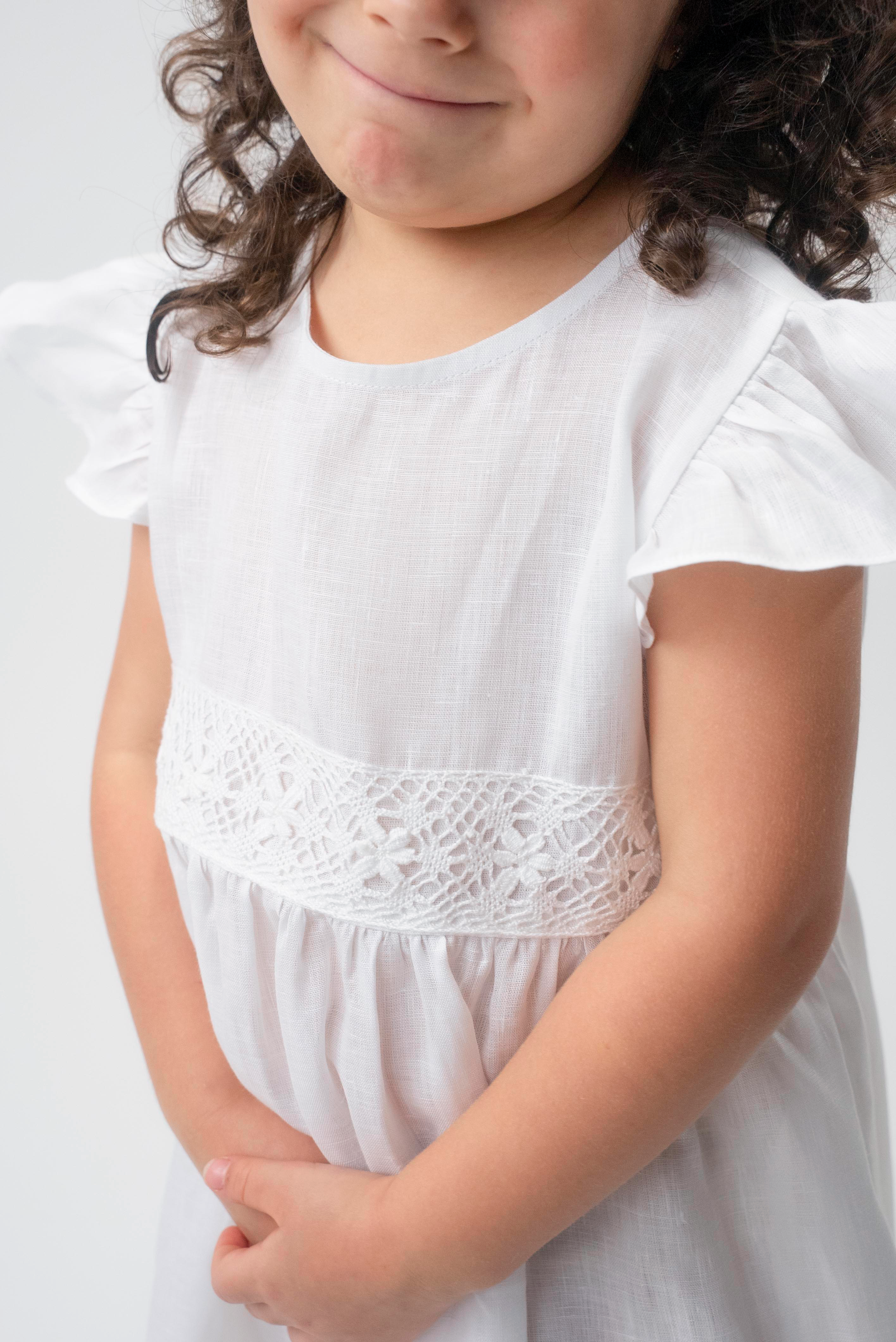 Detalhe da renda de bilro branca na cintura do Vestido Clara infantil em linho, com manga em babado.