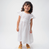 Menina vestindo Vestido Clara infantil em 100% linho branco com renda de bilro na cintura e mangas em babado.