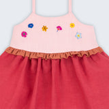 Vestido infantil em linho cereja e rosa com flores bordadas à mão e detalhe franzido na cintura, visto de frente em detalhe.