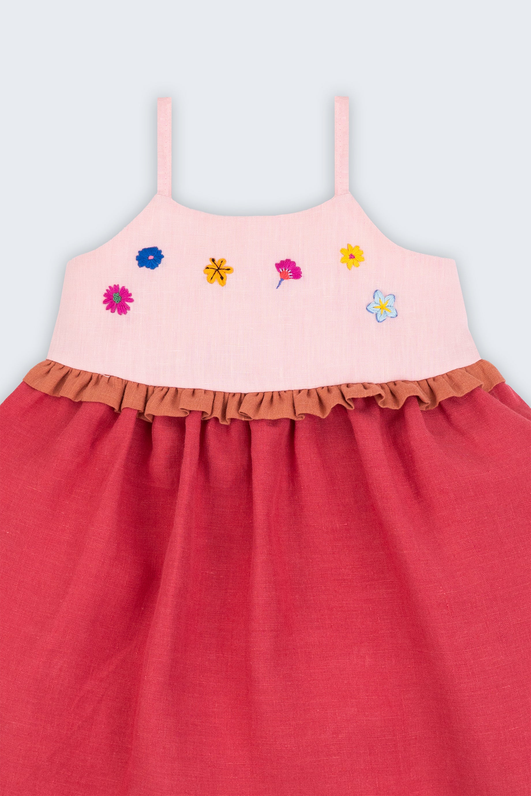 Vestido infantil em linho cereja e rosa com flores bordadas à mão e detalhe franzido na cintura, visto de frente em detalhe.