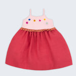 Vestido infantil em linho cereja e rosa com flores bordadas à mão e detalhe franzido na cintura para meninas, visto de frente.