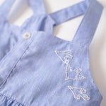 Detalhe do bordado de pássaros do vestido infantil em linho e algodão azul.